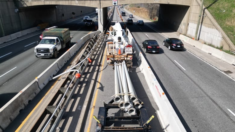 A drone view of the Gardiner Expressway construction shows cars passing a number of pipes on a closed section of the roadway.