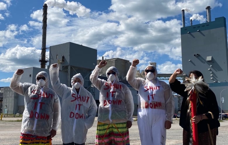 People are seen wearing white jackets with red paint that says 