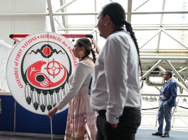 Attendees walk past a banner  at the Assembly of First Nations annual general assembly  in Montreal, Tuesday, July 9, 2024.