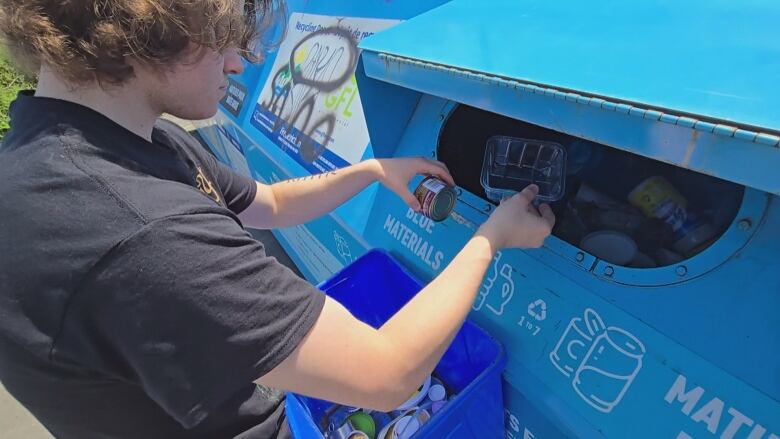 A man recycling at blue bins