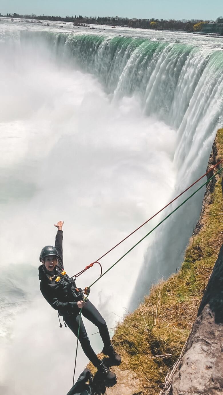 A woman wearing climbing gear hovering over the Niagara Falls