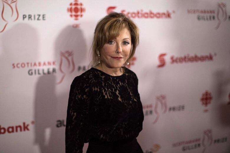 A woman in a black dress poses for cameras.