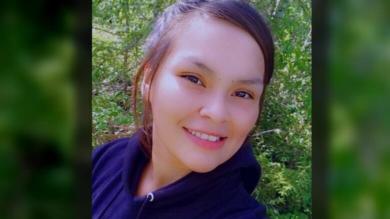 A photo of a young woman with a pony tail and blue hoody, smiling.