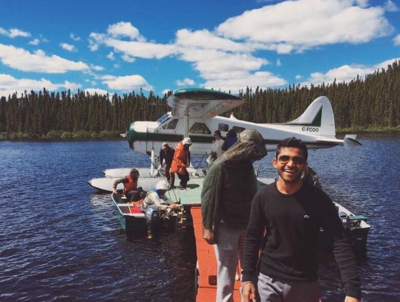 A group of people step off a float plane on a lake with trees surrounding it. 