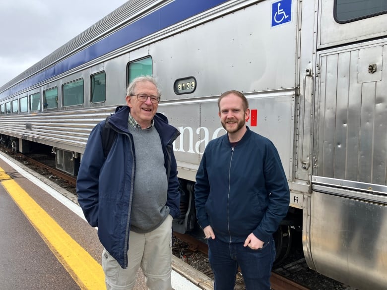 Two men standing in front of a train.