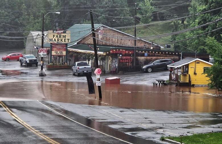 A photo shows an impassable road due to flooding.