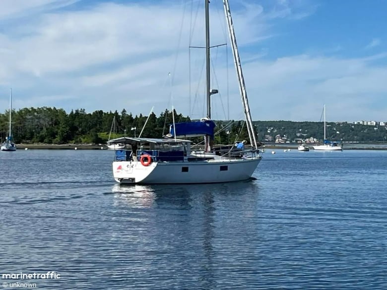 A sailboat can be seen in the ocean, with the shoreline in sight.