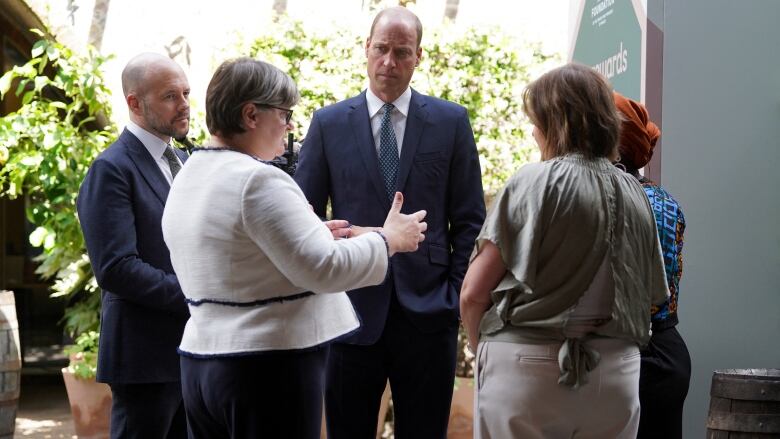 People stand in a circle and listen as one person talks.