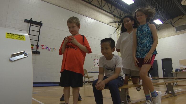 Four children stand in front of a vent