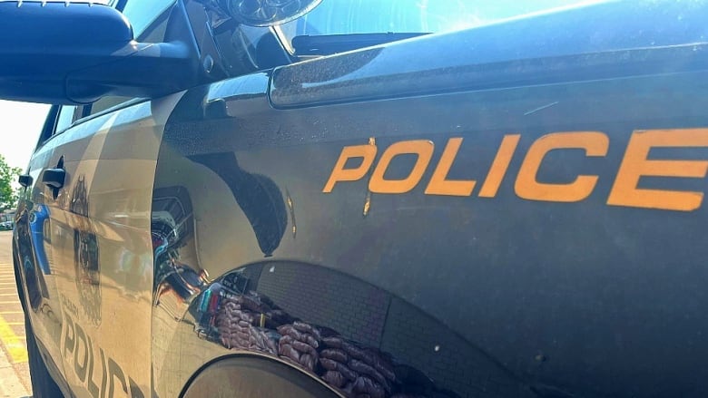 The passenger door and left side of a Calgary Police Service car with the word police written in yellow.