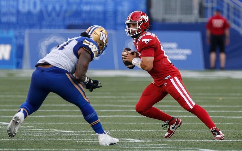 A man wearing a red football uniform tries to dodge the opposing player. 