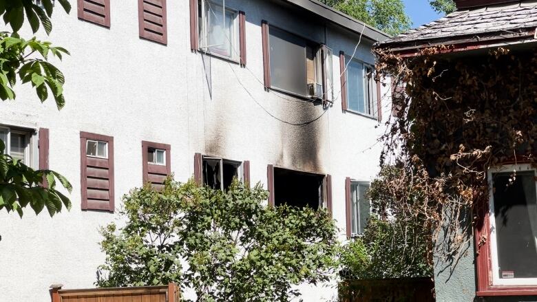 Smoke damage is visible from windows of an apartment building.