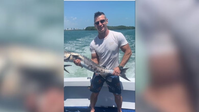 A white man carries a large fish on a boat.