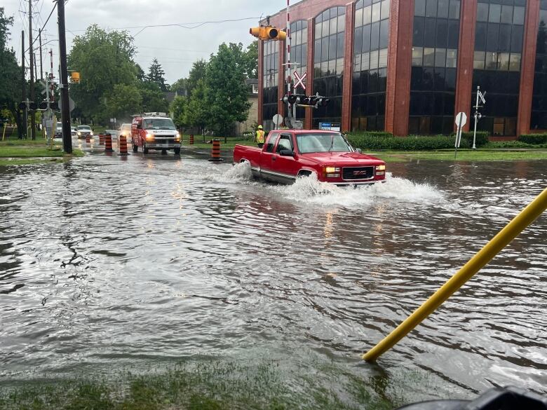 Red truck driving into a flooded intersection