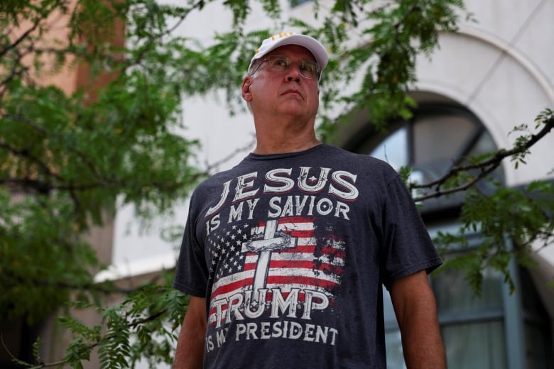 Man with cap and T shirt that has a flag and says 