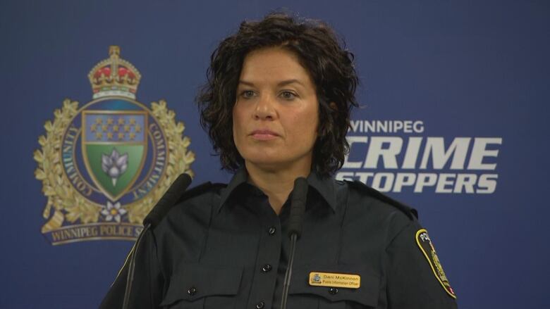 A woman in a police uniform looks forward.