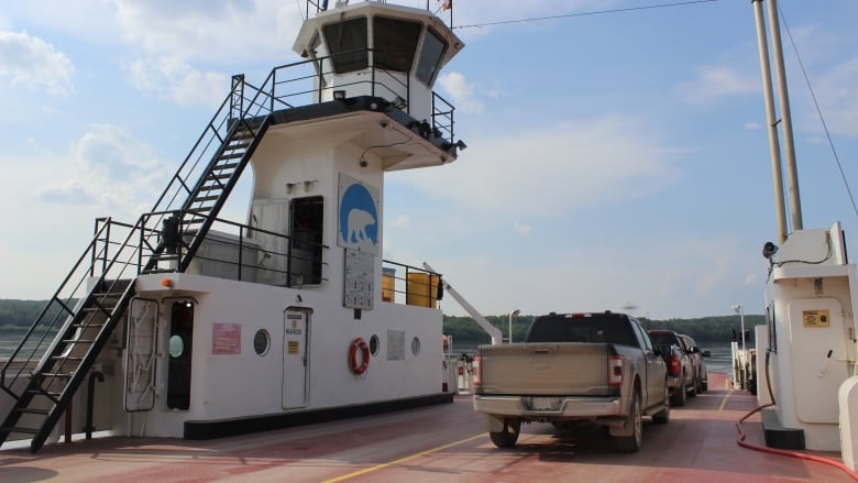 A shot of three trucks on board a red surface. An observation tower-like thing is on the left. A river can be seen in the background.