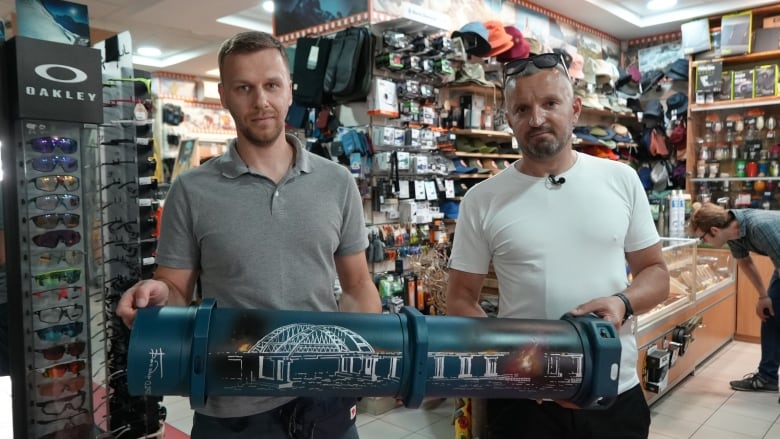 Denys Martyniuk (left) and Petro Shamborovskyi hold a casing from a 155 mm shell that has the image of the Kerch bridge, which connects Russia to Crimea, painted on it.  