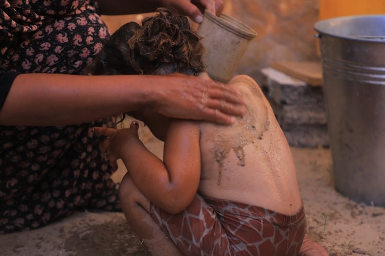 A little girl crouches near her mom in a tent 