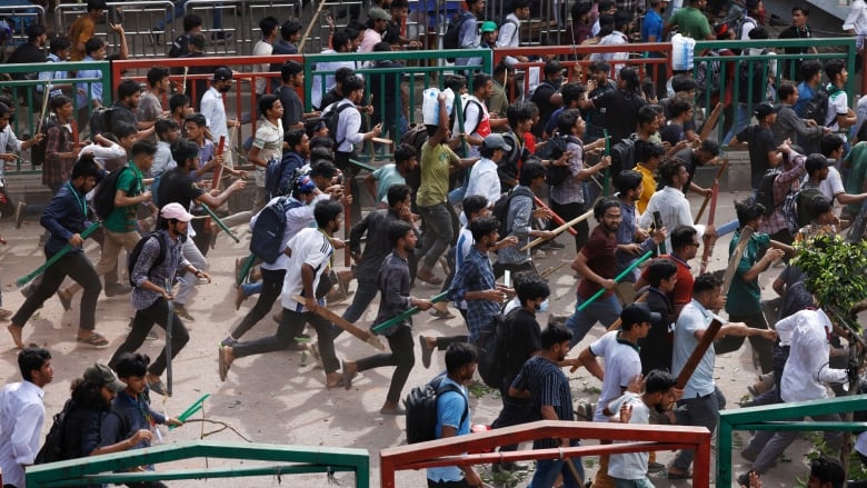 A photo taken at eleveation shows dozens of people who appear to be running down a road, some holding large sticks and other weapons.