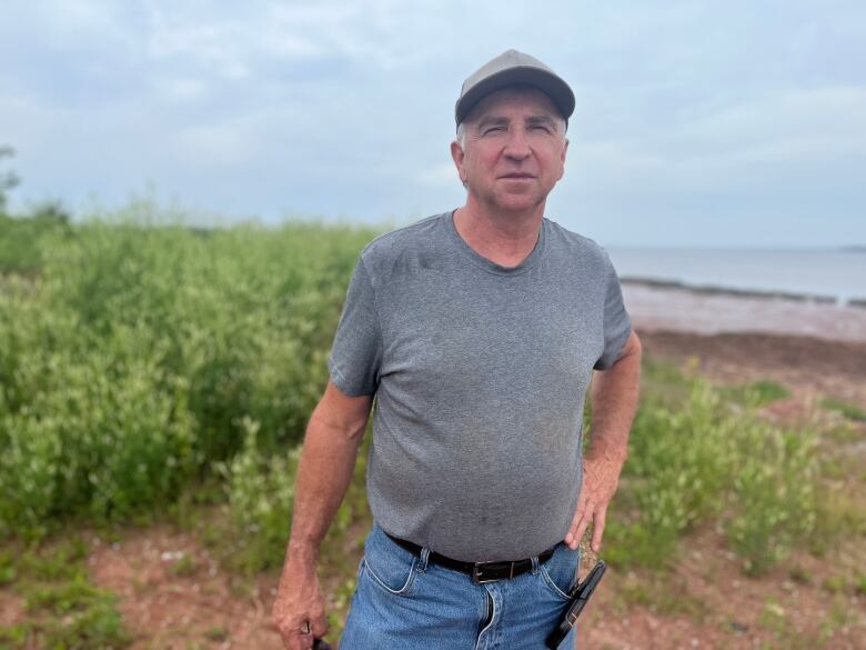 Man in grey shirt standing on shoreline.