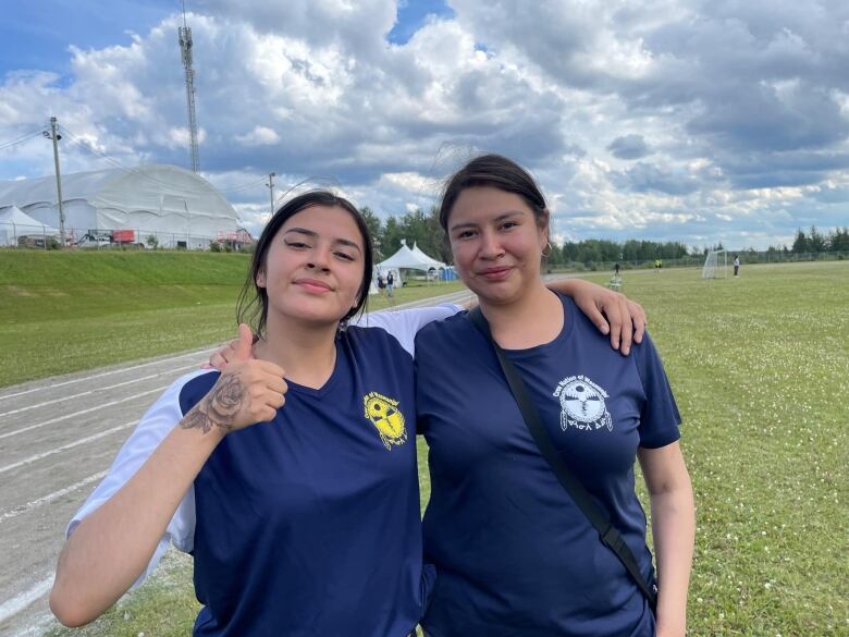 Two sisters standing on a track and field