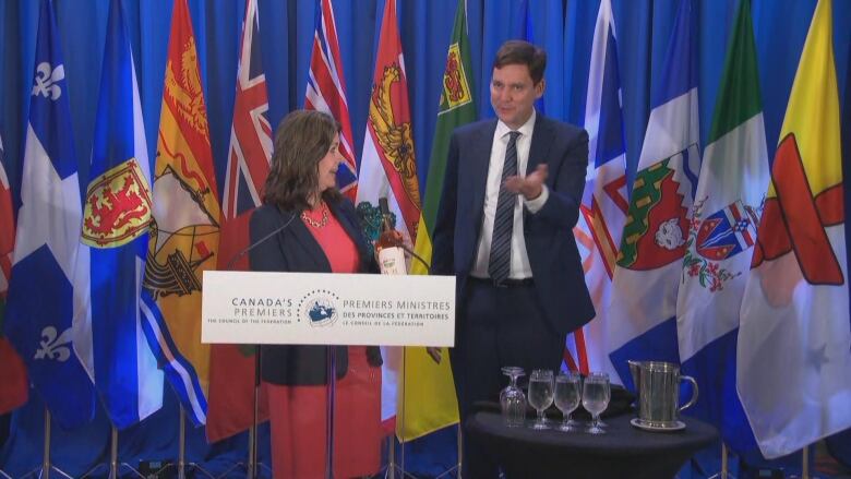 Two people at a podium, one holding wine.