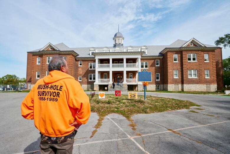 Residential school survivor stands in front of former Mohawk Institute.