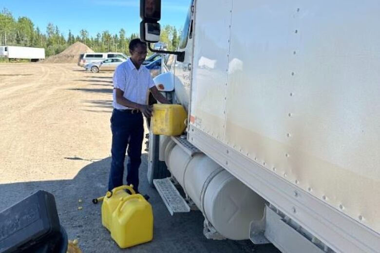 A man pouring yellow fuel canisters into a white truck. 