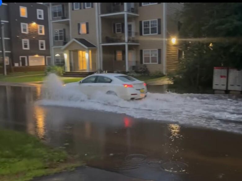 A car drives down flooded Harley Street in Charlottetown.