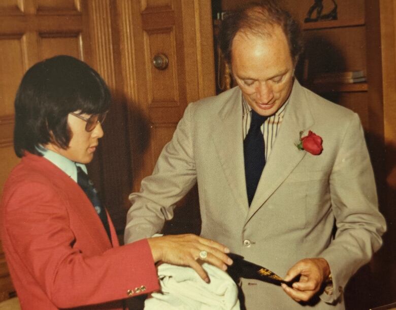 A young person shows something to an older person in a fancy wooden room