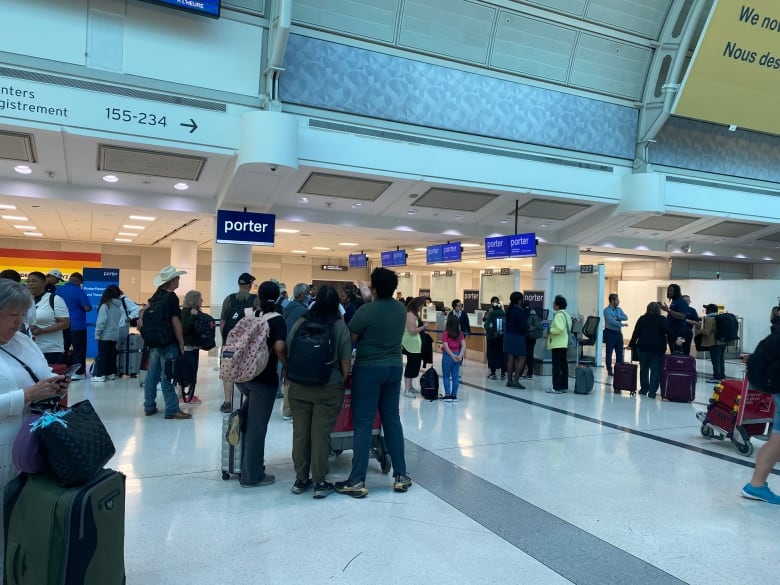 People are shown carrying luggage, with terminal flight arrival and departure boards also visible, in this photo.