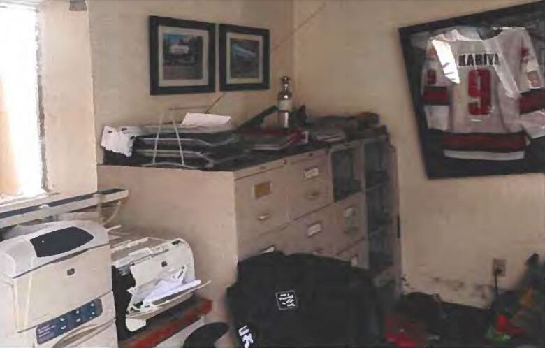 A metal filing cabinet against a wall in an office, with drawers of files missing.