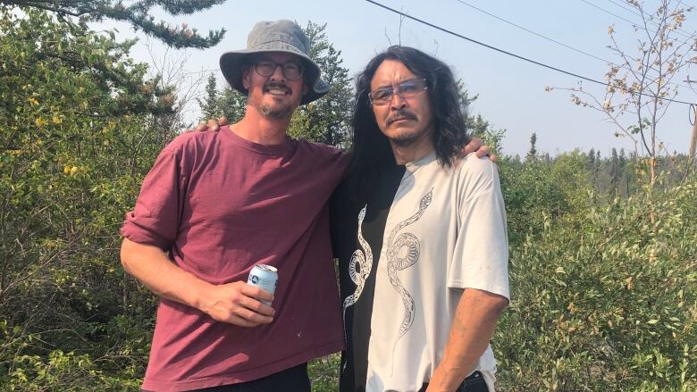 Two men pose for a picture with trees in the background