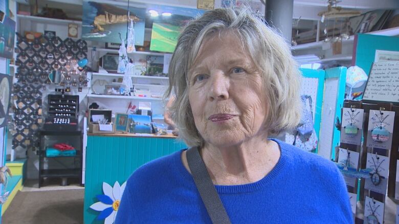 Woman in a blue sweater stands in a store.