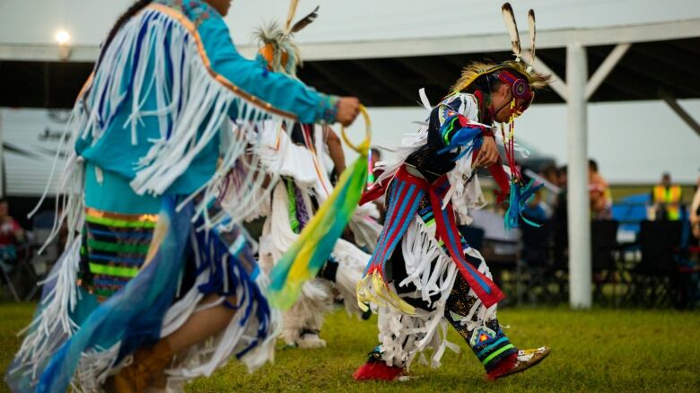 Three men dance in a powwow.