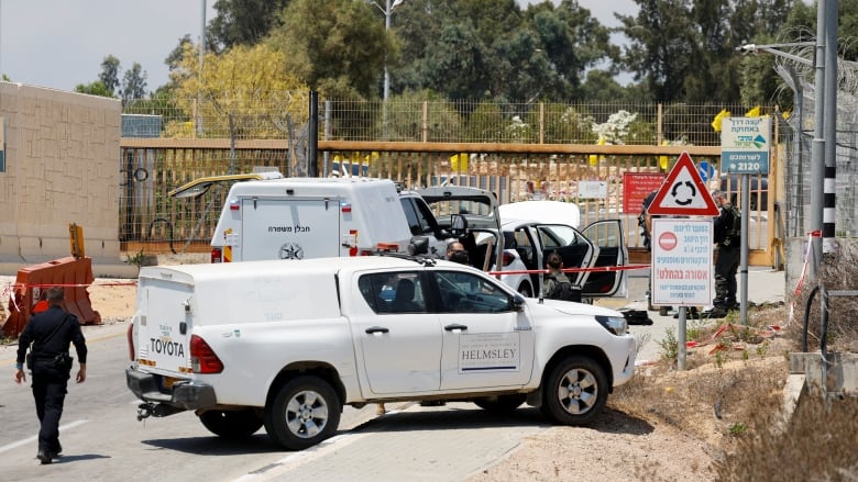 Two vehicles, a person in a police-type uniform and police tape are shown at a gated area.