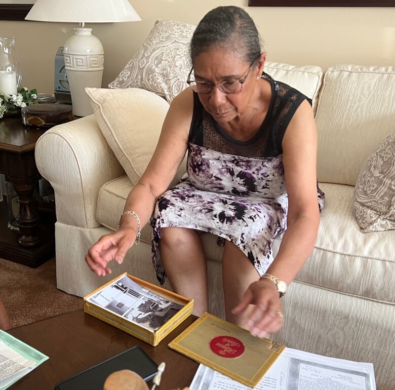 A woman sitting on a sofa looking at old photographs.