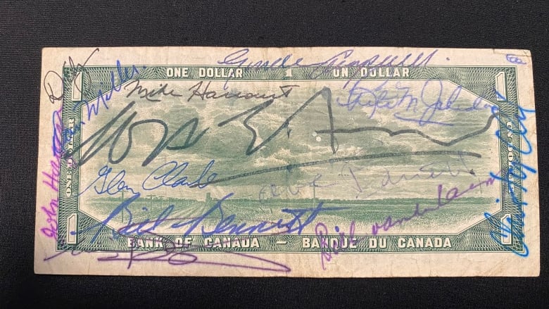 A dollar bill with several signatures on it. 