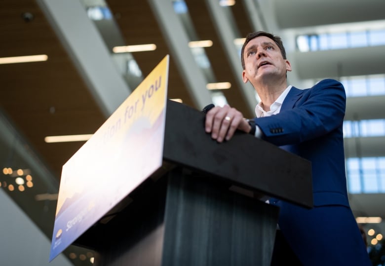 A tall man speaks at a podium. He is pictured from below.