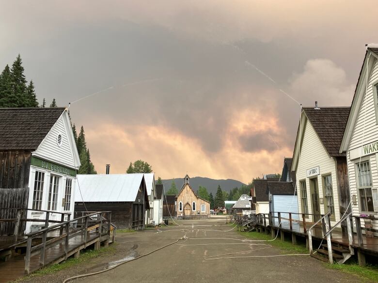 Hoses spray water on houses as smoky conditions linger.