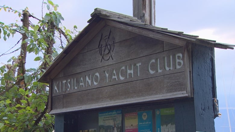 A board reading 'Kitsilano Yacht Club' is seen on a sunny day.