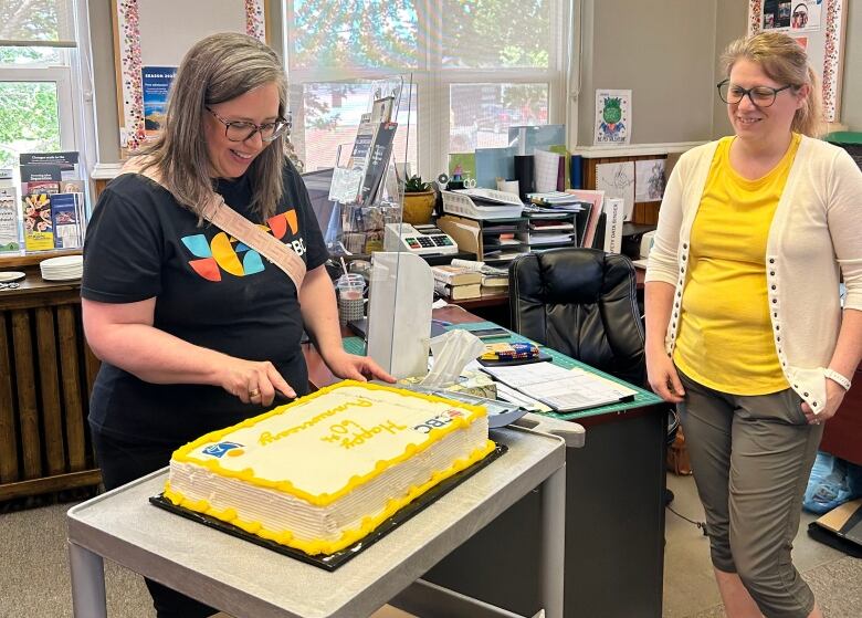 two women cutting large anniversary cake