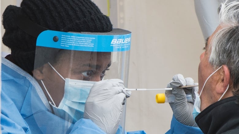 A health-care worker prepares to swab a man at a walk-in COVID-19 test clinic