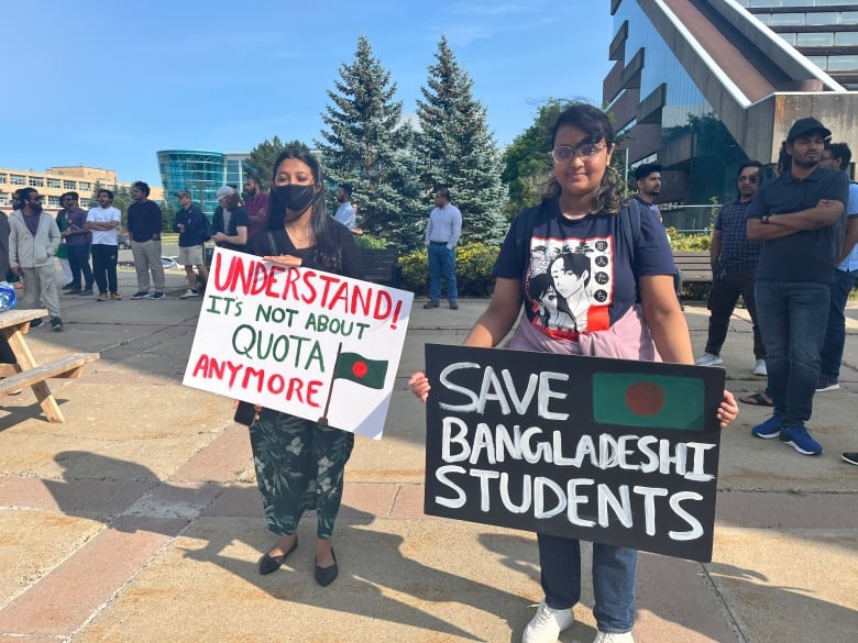 Two women holding signs. One says 