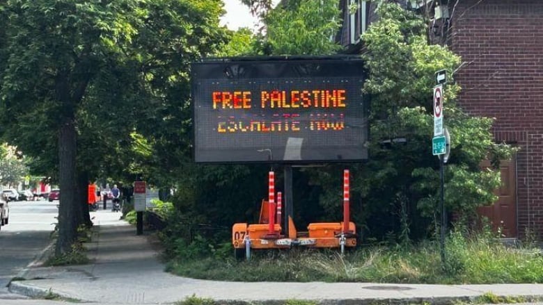 An electronic traffic message board reads, Free Palestine, Escalate now. 