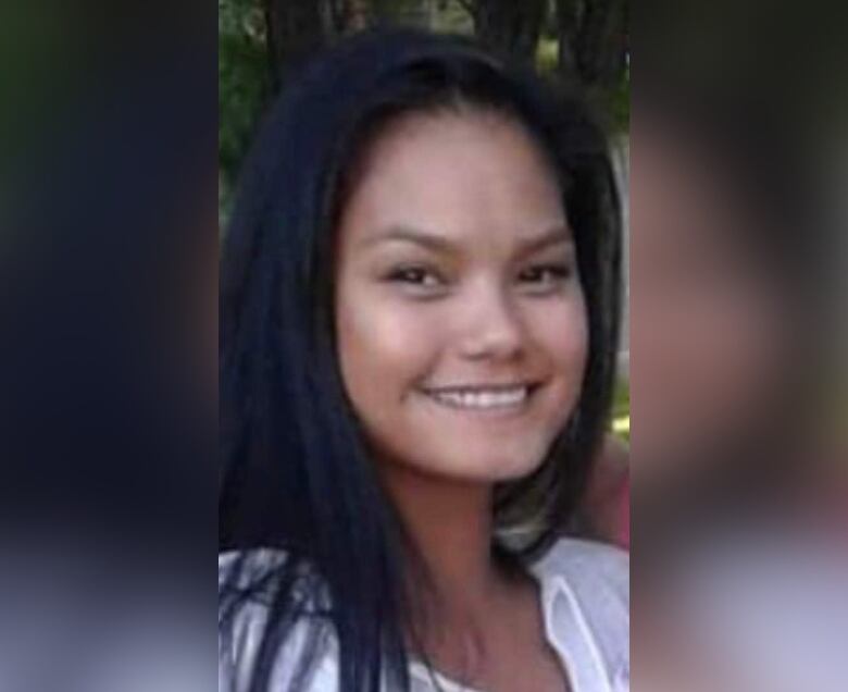 A woman with long black hair and brown eyes wearing a white shirt. 