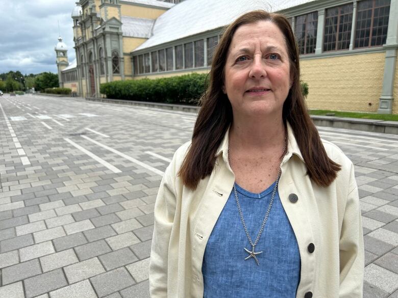 A woman in a blue shirt and white jacket.