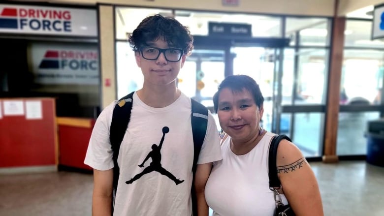 A young man and his mother pose for a photo 