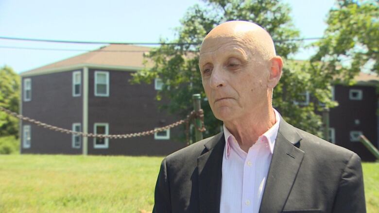 Bald man wearing suit standing outside